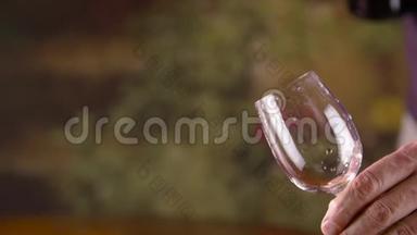 男人用手从瓶子里往杯子里倒红酒。 喝红酒的人